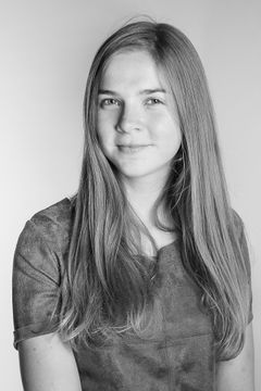 Portret van een jonge vrouw met lang haar in een suède jurk, zwart-wit