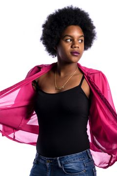 Vrouw met afrokapsel trekt een roze blouse open over een zwart hemd, witte achtergrond