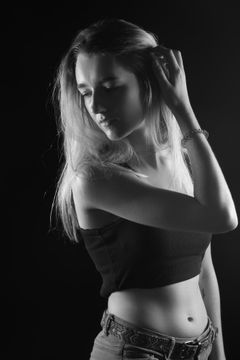 Vrouw met lang blond haar en een hand in haar nek, zwart topje, zwart-wit