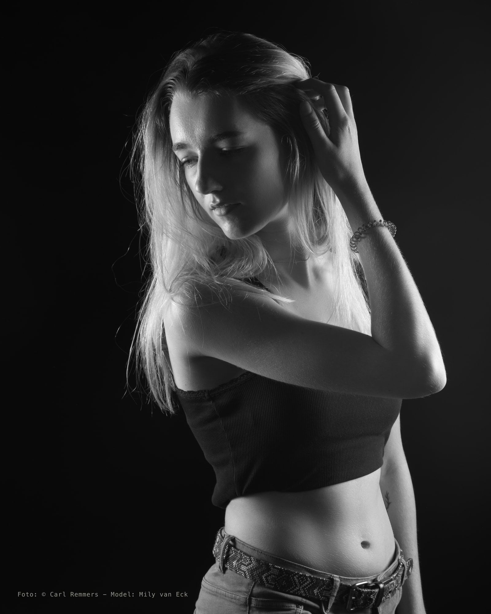 Vrouw met lang blond haar en een hand in haar nek, zwart topje, zwart-wit