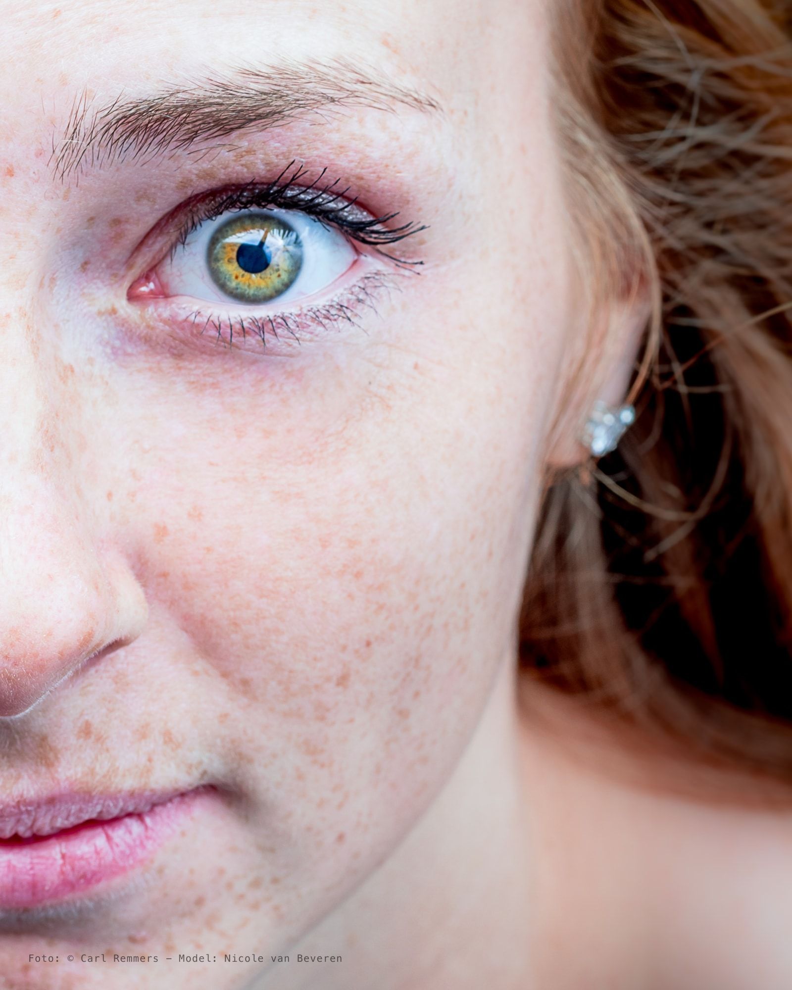 Close-up van een oog met sproeten en een groenbruine iris