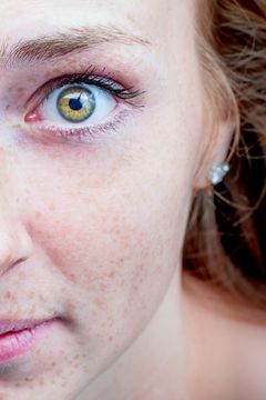 Close-up van een oog met sproeten en een groenbruine iris