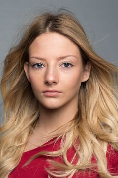 Vrouw met blond golvend haar in een rode top, grijze achtergrond