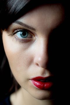 Half gezicht in de schaduw, een blauw oog en rode lippen