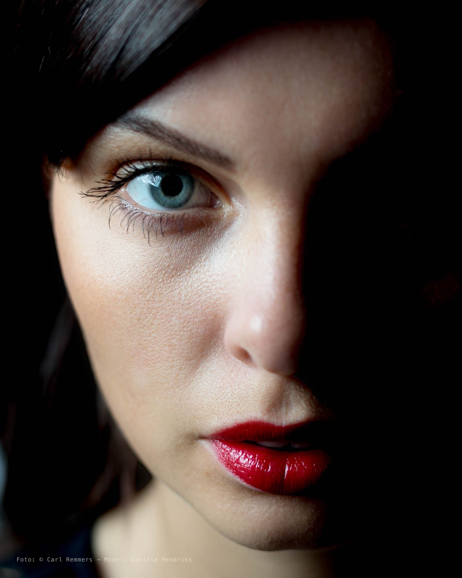 Half gezicht in de schaduw, een blauw oog en rode lippen