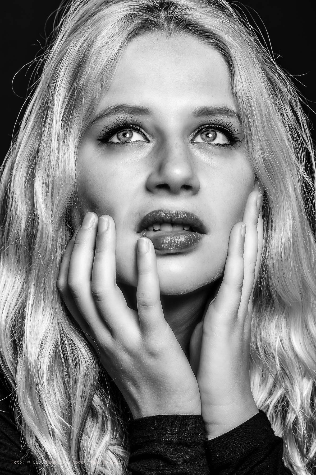 Woman with her hands alongside her face looking up, black and white