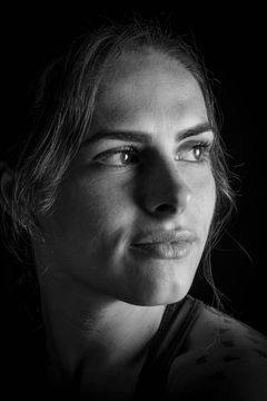 Zijportret in strijklicht met een tatoeage op de schouder, zwart-wit