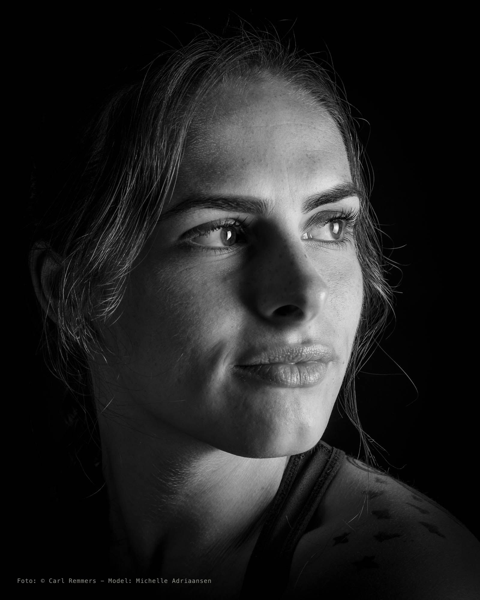 Zijportret in strijklicht met een tatoeage op de schouder, zwart-wit