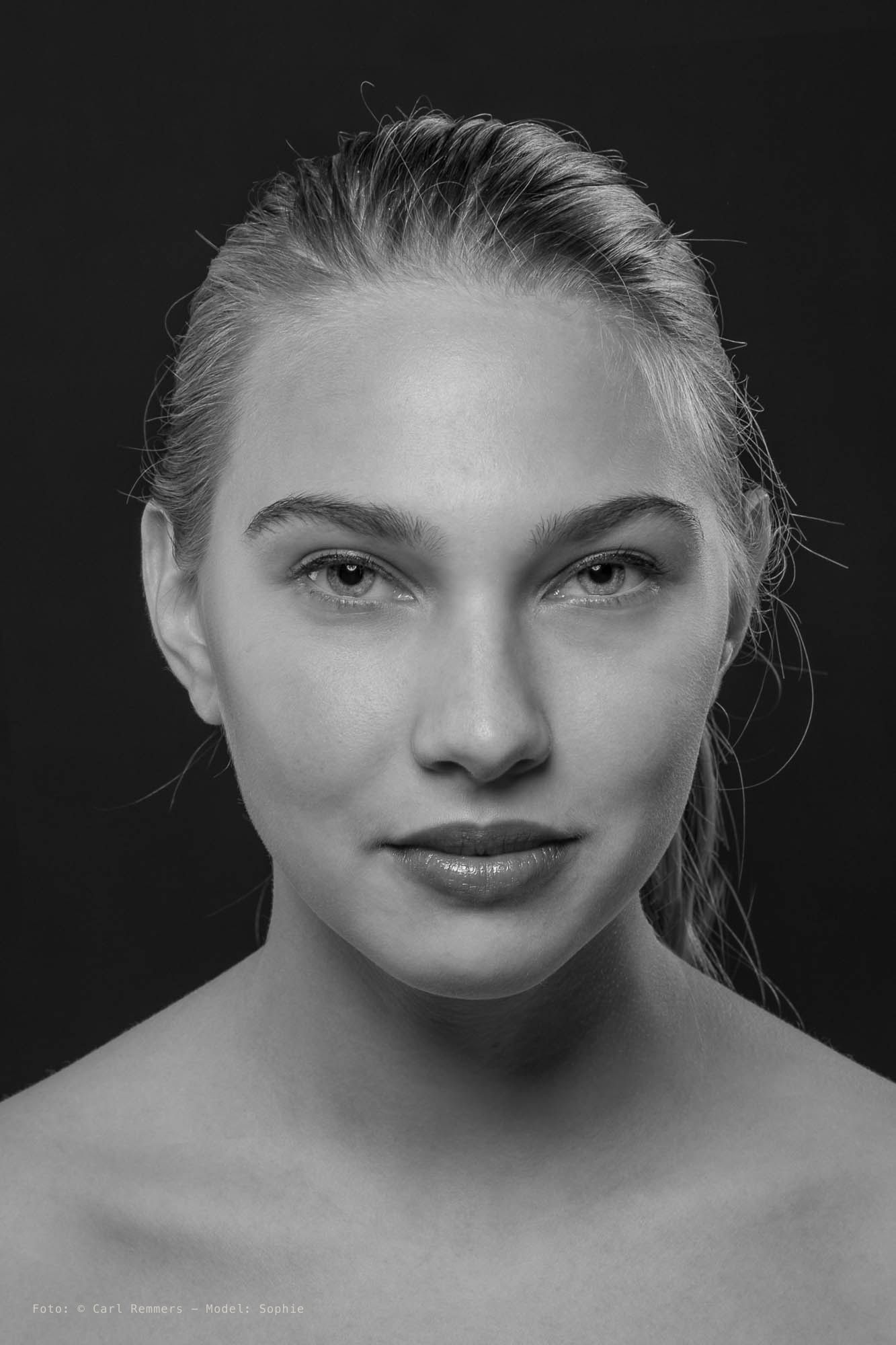 Portret met strak naar achteren gekamd haar en blote schouders, zwart-wit